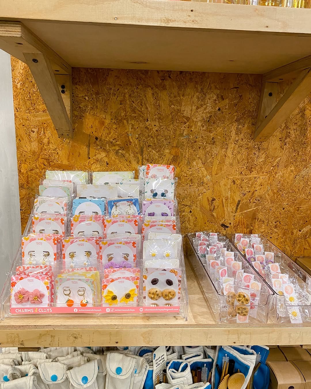 Product display shelf at partner store showing multiple earring card sets in branded Charms and Clays packaging