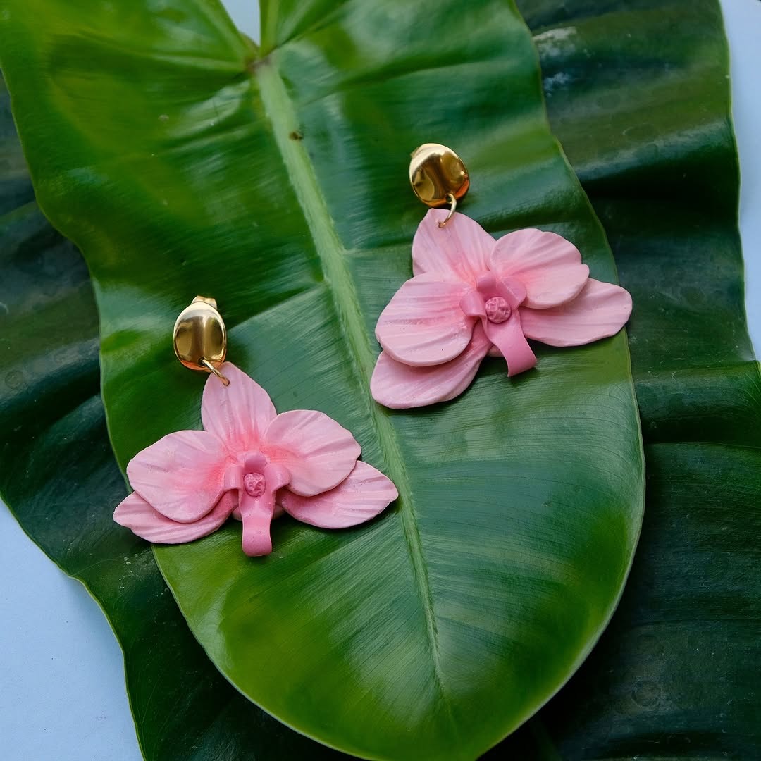 Pink orchid drop earrings with gold dome stud on tropical leaf